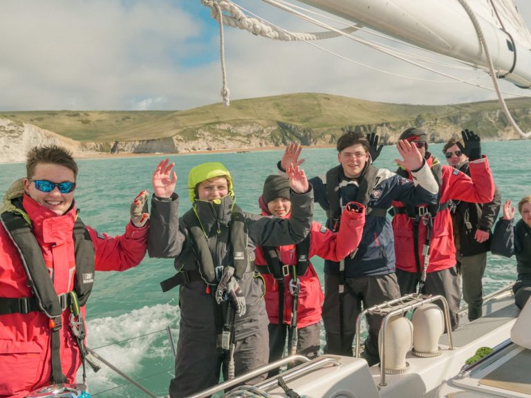 group photo holding hands up with Cowes, isle of wight in the background